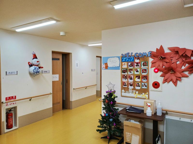 写真が飾られた廊下の壁の前には小さなテーブルが置かれていて、クリスマスツリーや雪だるまも飾られている。