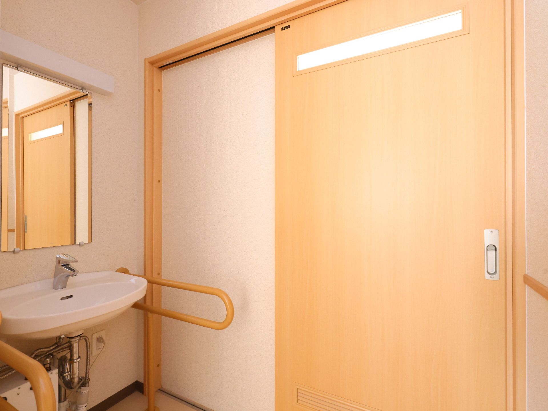 鏡が設置され、手すりが付いている共有スペースの洗面台