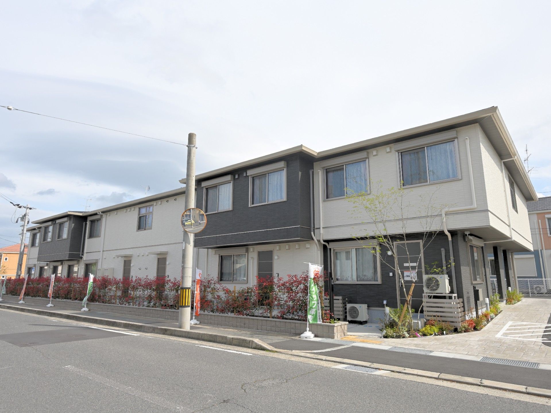 モノトーンの２階建ての建物の周辺には生垣があり、駐車場も完備されている。