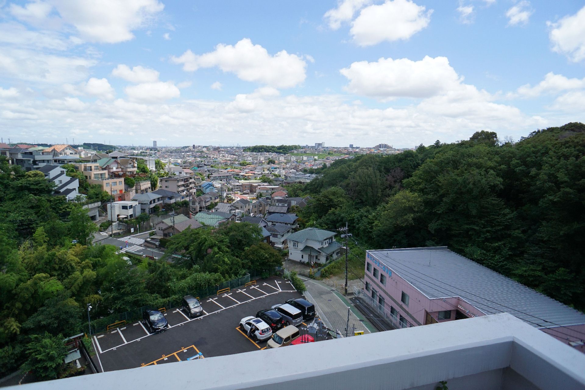青空と住宅街と手前に駐車場が見える景色