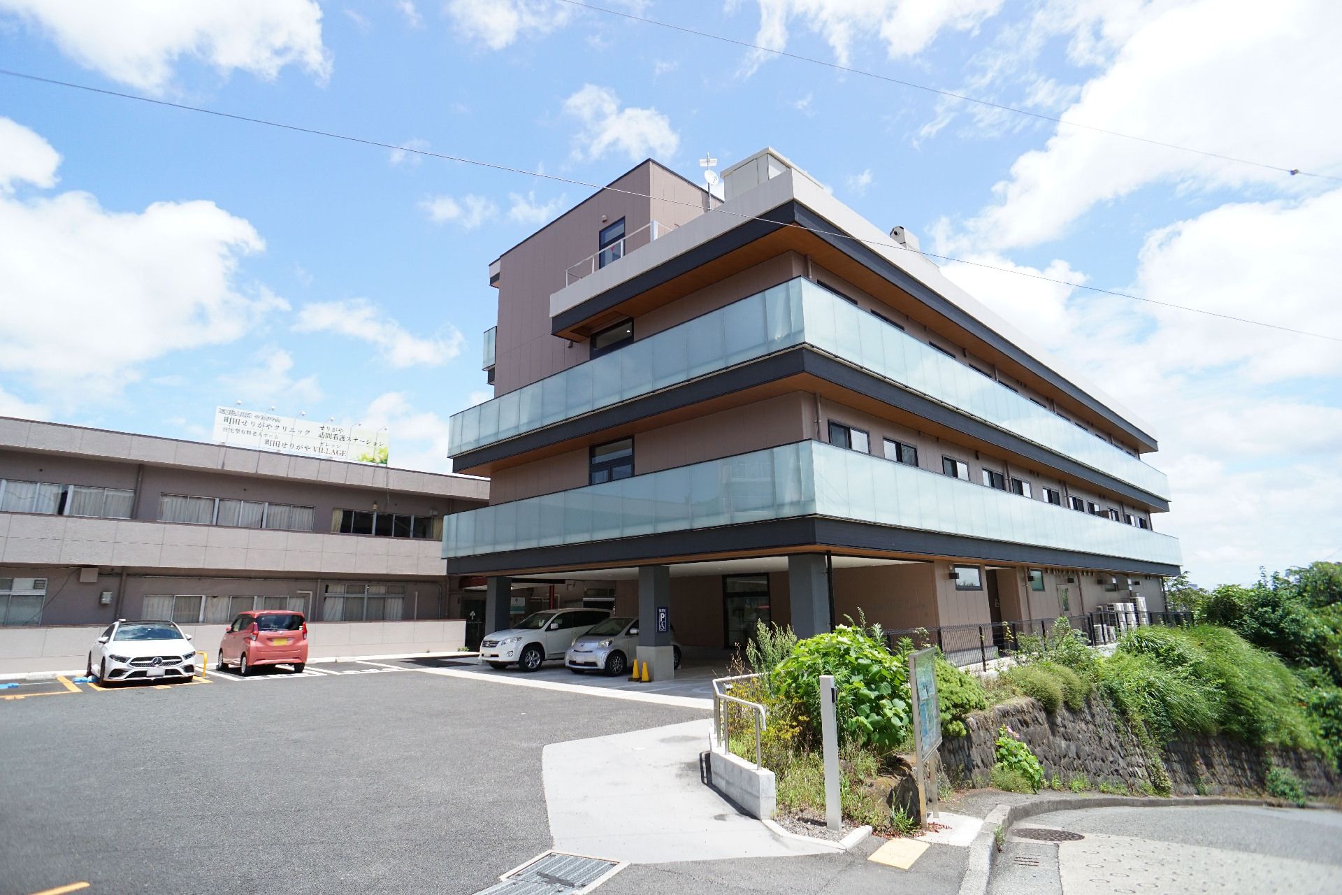 青空の下にある大きな駐車スペースと３階建ての建物