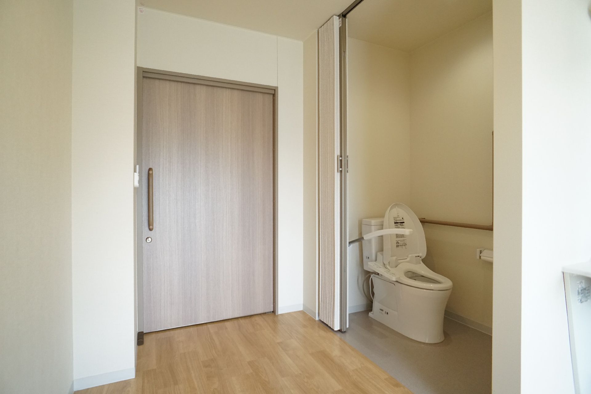 フローリングの部屋から見たスライド式の扉の奥にあるトイレ