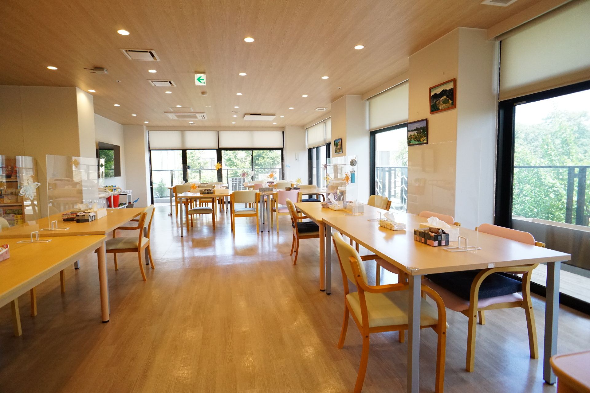 壁の二面が窓で机と椅子がたくさん置かれた部屋
