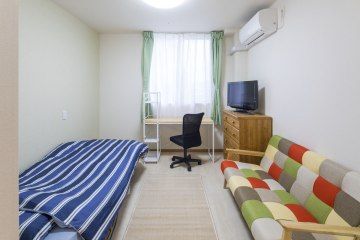 お部屋にはベッド、カラフルなソファ、デスク、テレビが設置