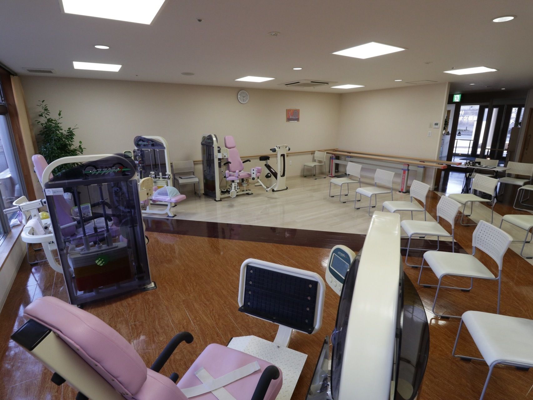 広々とした開放的な機能訓練室である。さまざまな種類のリハビリ器具が設置されている。複数の椅子が用意されている。