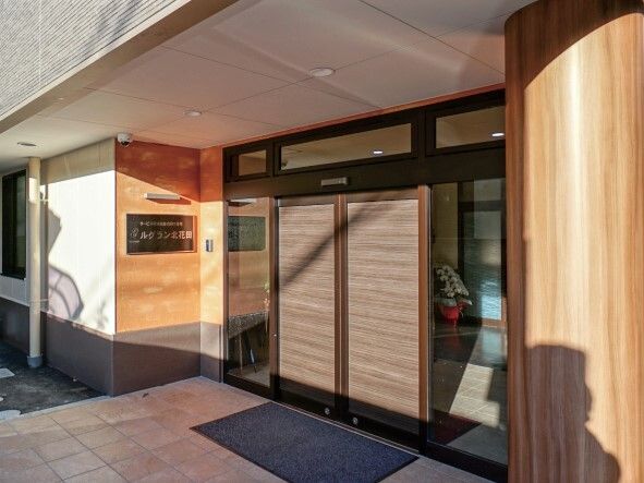 玄関には自動ドアが付き、風除室もある。マットが敷かれ、壁には住宅名が書かれたプレートもある。
