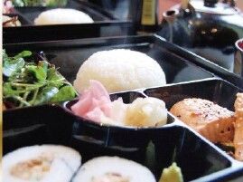 太巻き寿司とサラダと肉料理の入った弁当