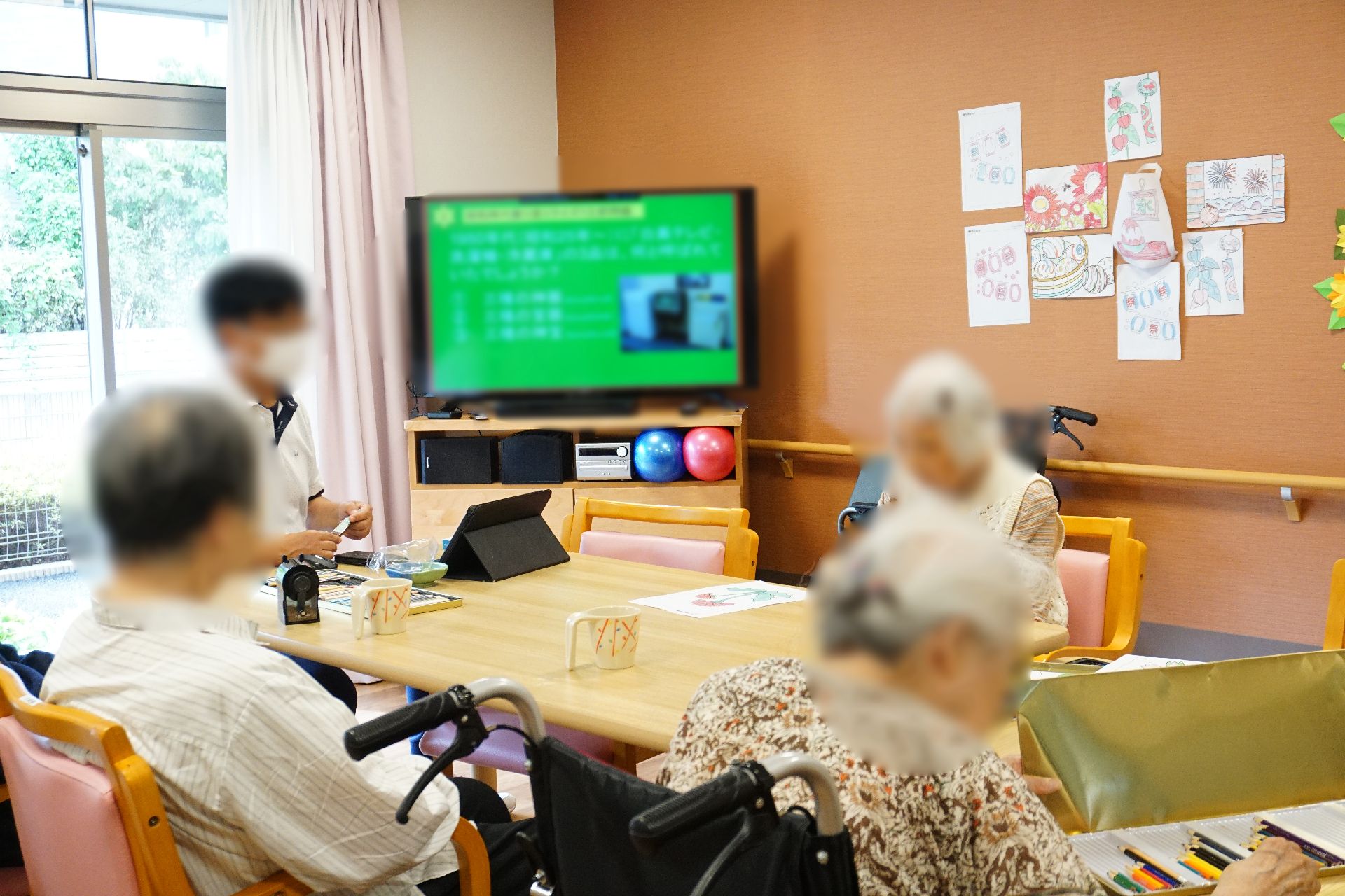テレビが設置され、テーブルの回りに入居者が集まっているリビング