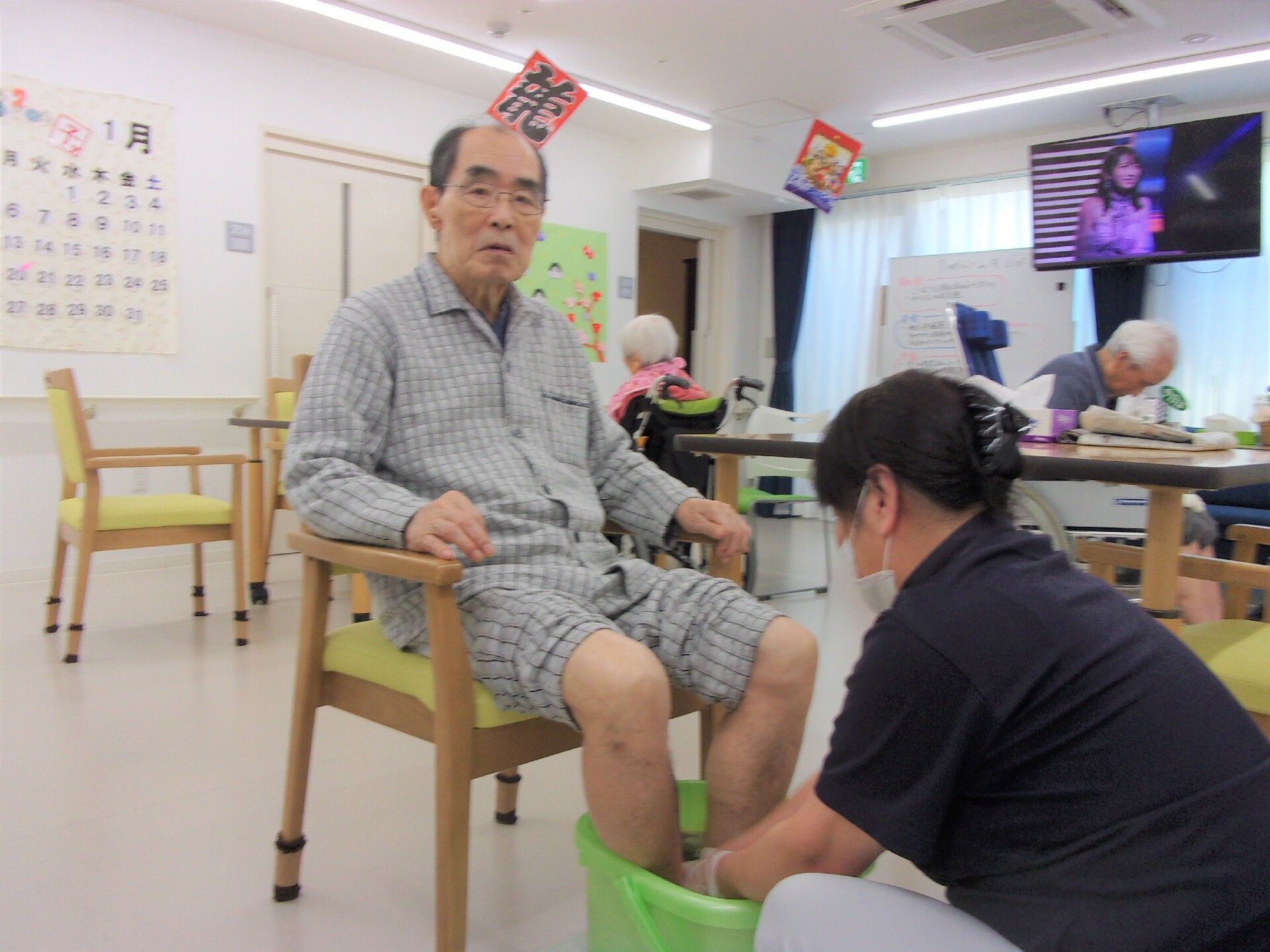 フットケアを受けている施設内の高齢男性の様子。手前にスタッフがいる写真