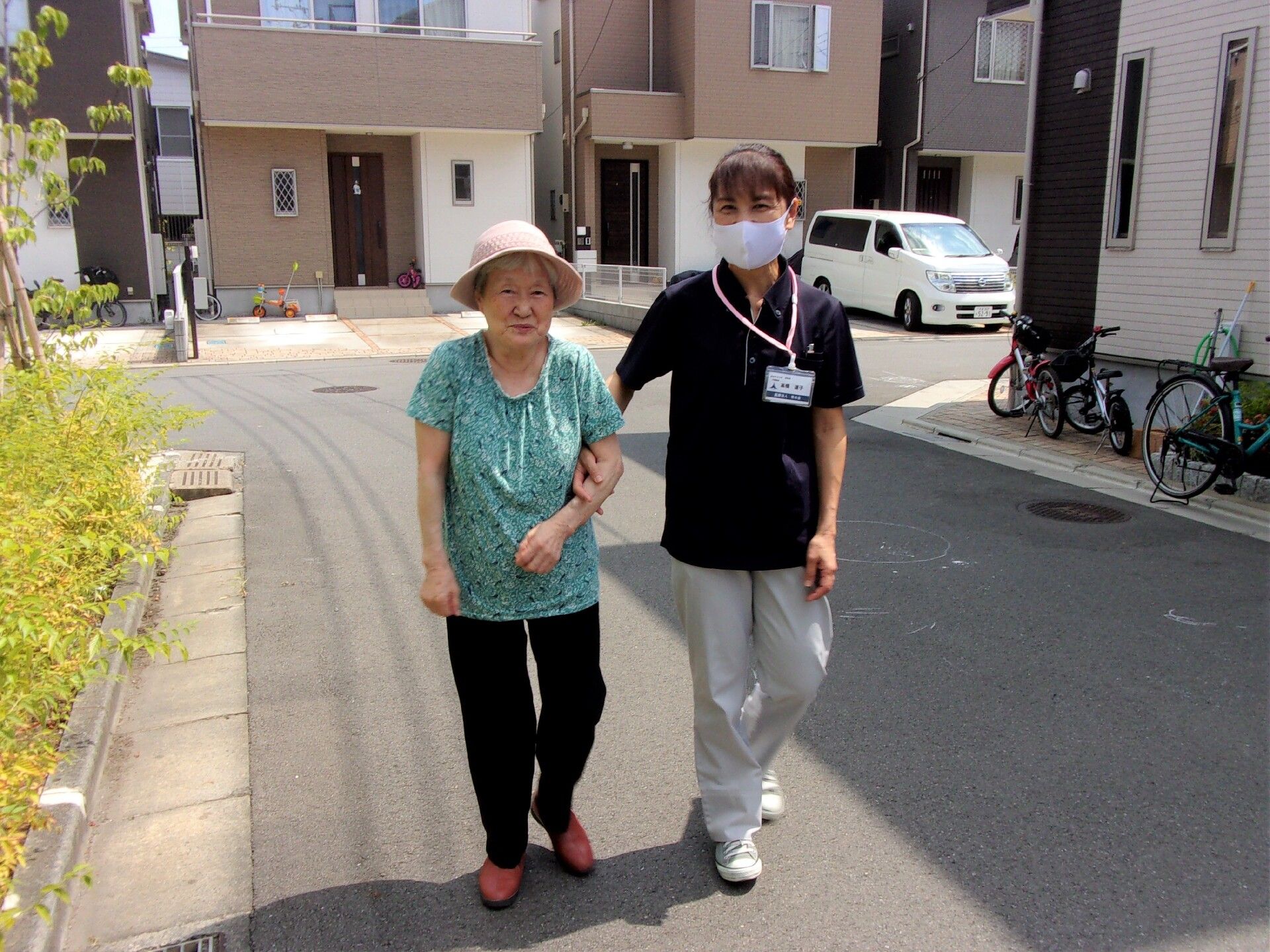 スタッフと高齢者が手を取り合いながら歩いている様子。施設の高齢者とスタッフ