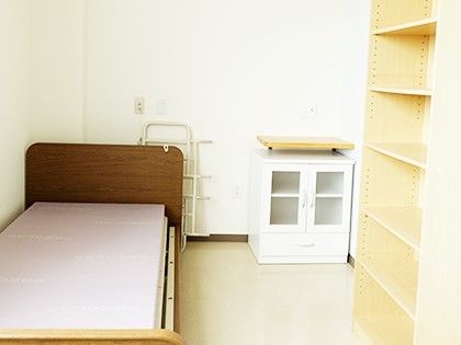 ベッドやたんすなどが置かれた入居前の施設内の部屋。一人用の部屋の写真