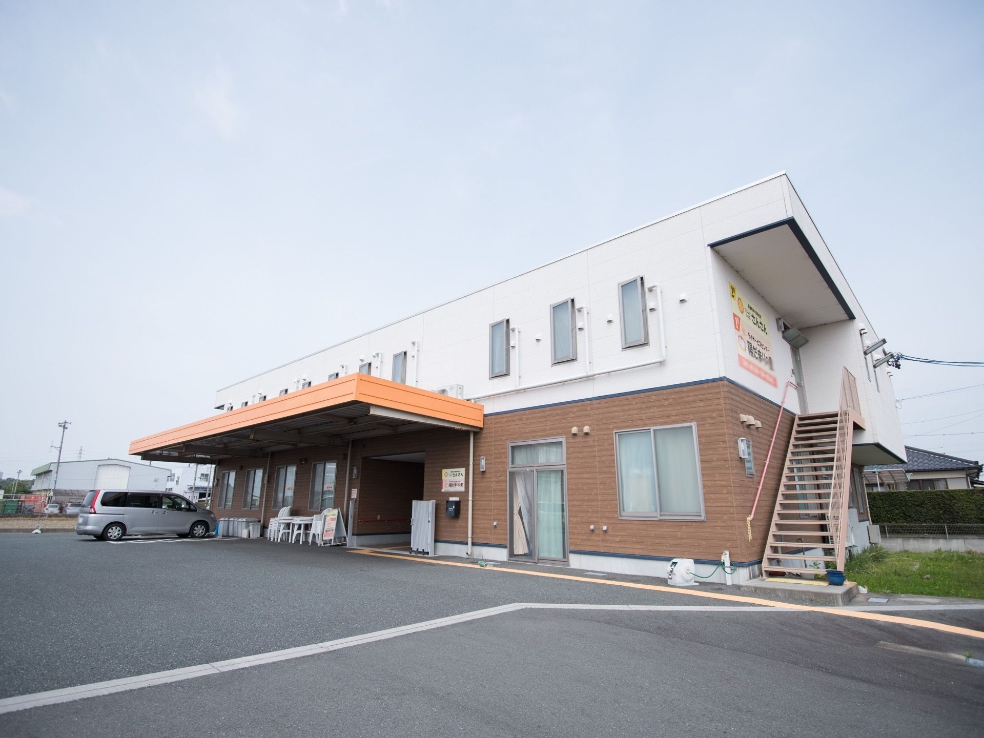 前面に広く駐車場を完備している2階建ての施設である。エントランスポーチが設置され駐車スペースも設けている。