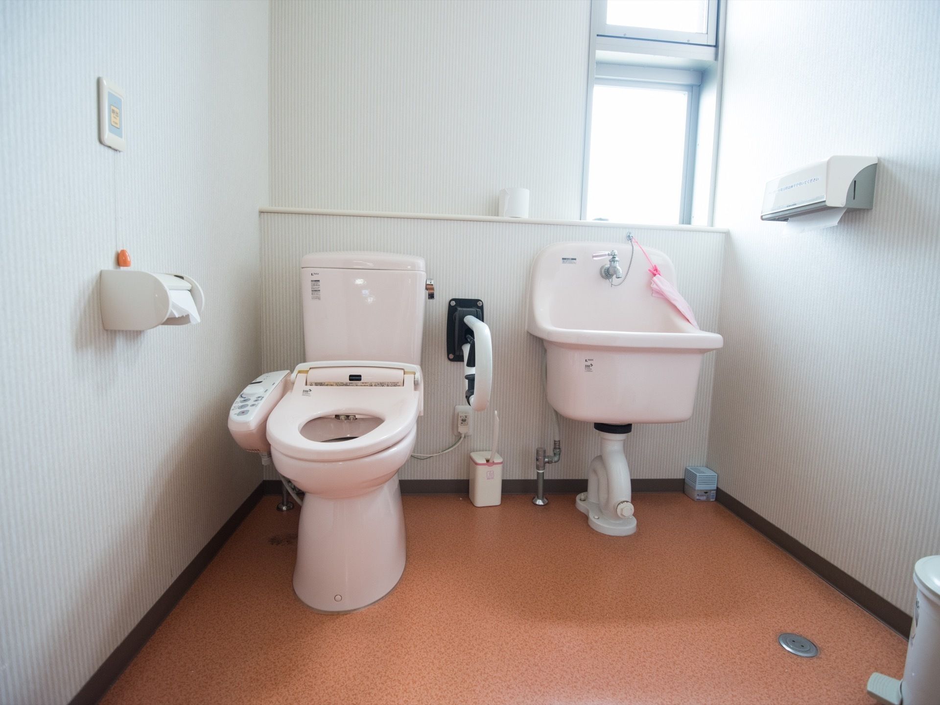 汚物専用の洗い場を設けたトイレである。完備している温水洗浄便座器のそばには、可動式手すりが設置されている。
