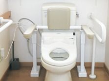 両側に立ち上がりようの手すりがついている施設内のトイレの様子