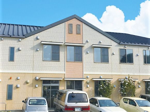 やわらかい色合いの壁と家のような屋根が印象的な建物の外観写真