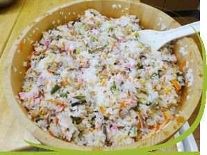 しゃもじで寿司桶に入った酢飯と具をかき混ぜている様子