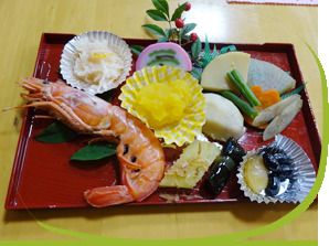 海老の焼き物や栗きんとんなどが盛り付けられたおせち料理