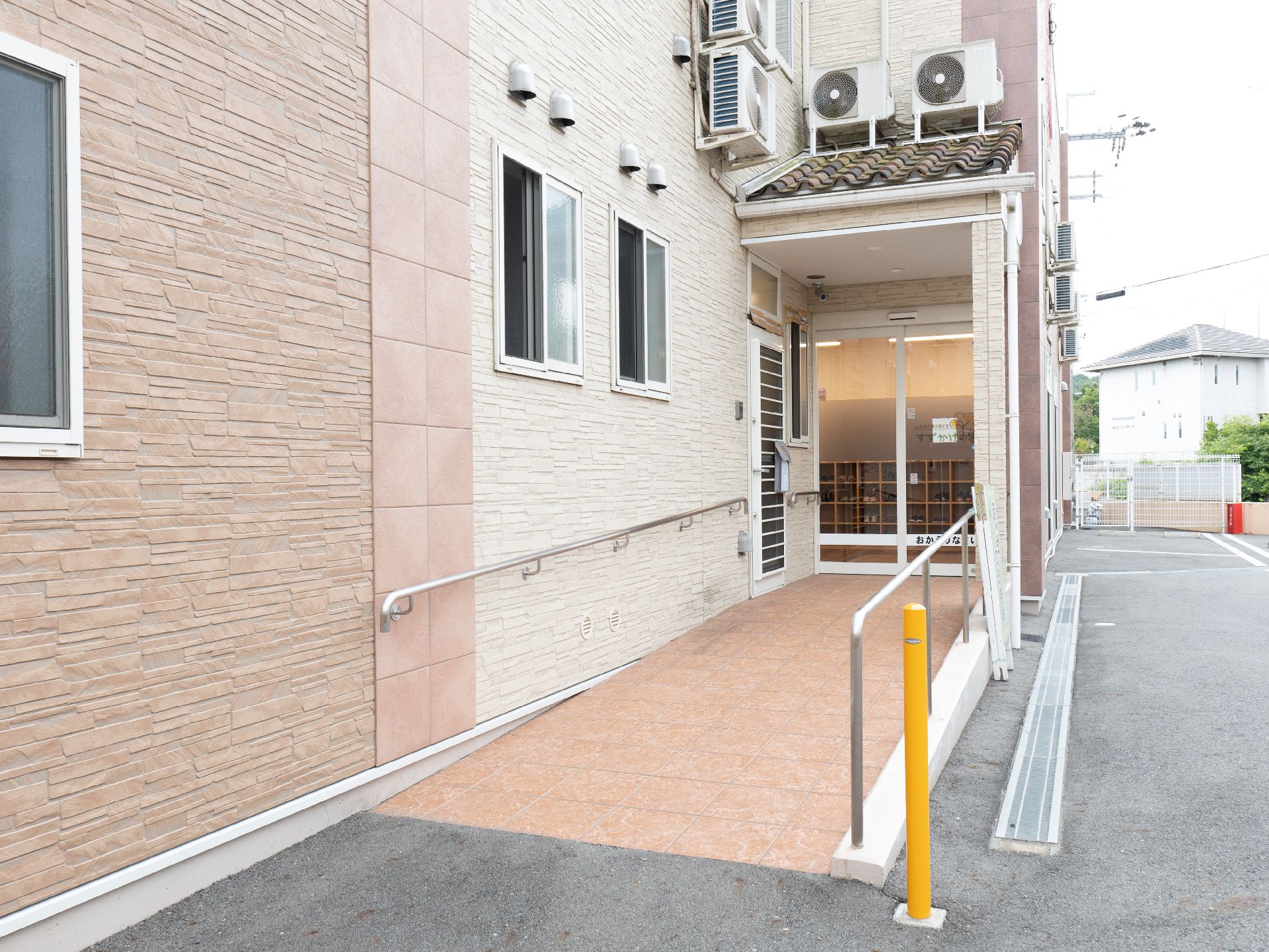 緑の多い屋外で散歩を楽しんでいる車いすの高齢女性と付き添いの若い女性スタッフ。