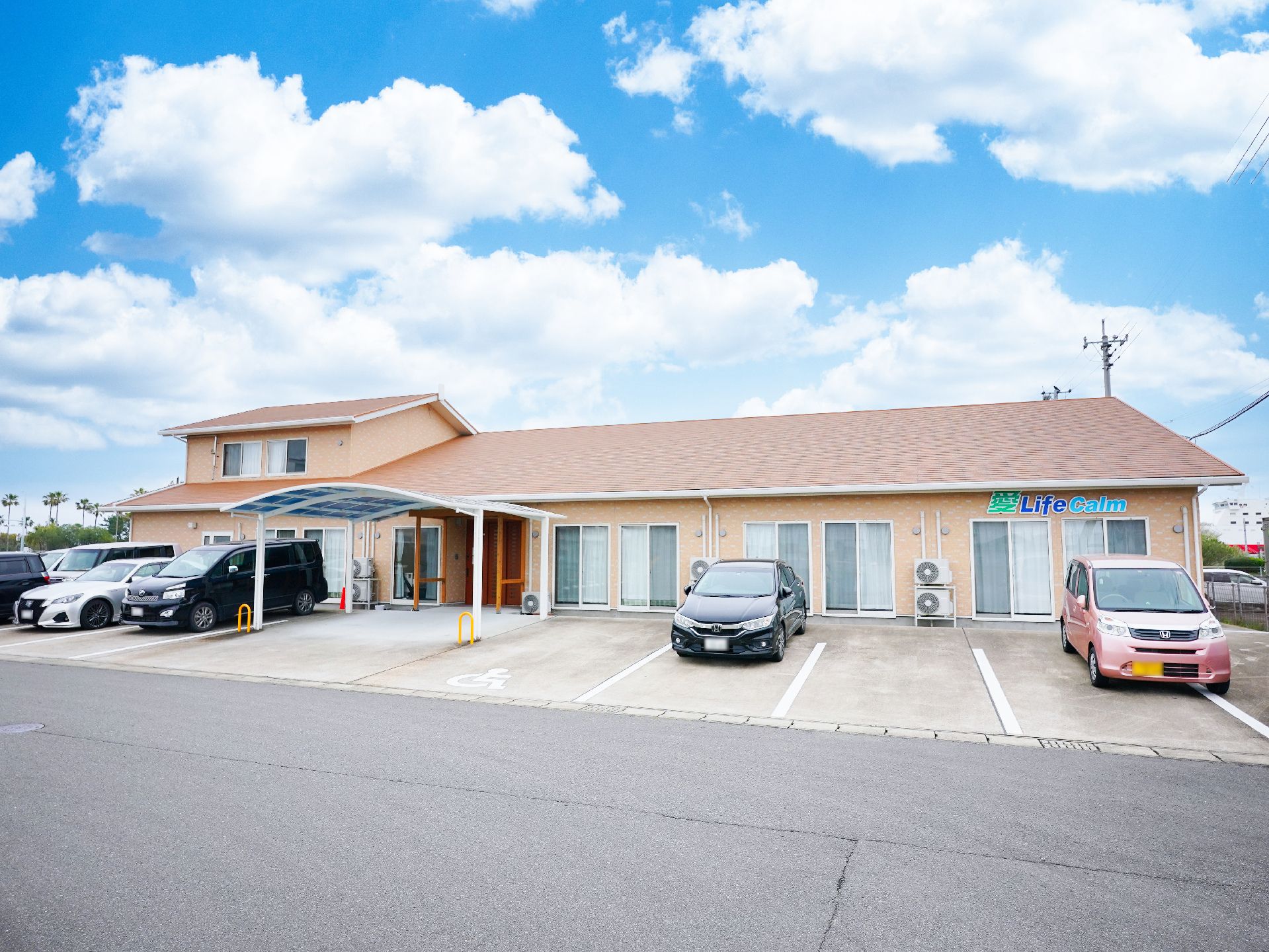 青空の下に建っているエンジ色の屋根が付いた平屋建ての建物