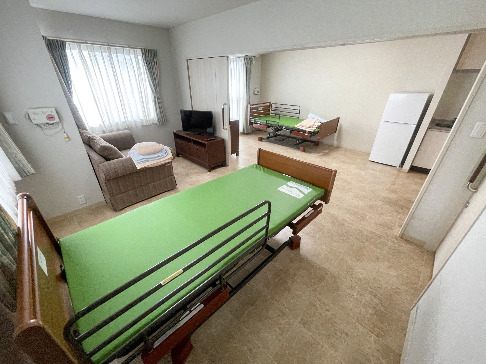 笑顔で屋外で過ごしている車いすの高齢女性と付き添いの高齢男性、男女のスタッフ。