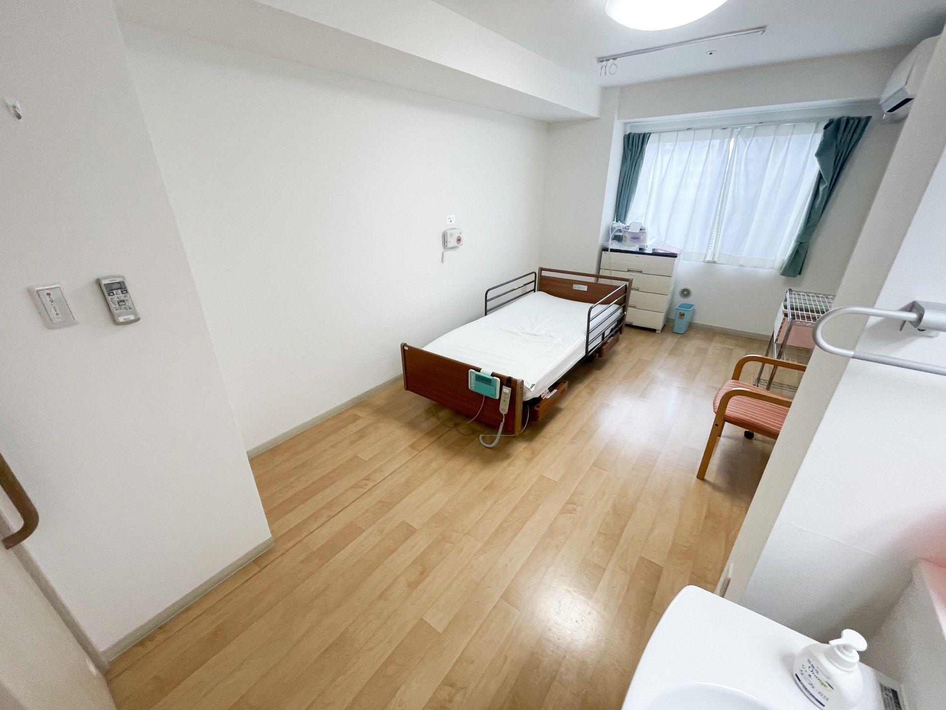 水の入ったコップを持って微笑んでいるエプロンを付けた女性スタッフと薬を飲もうとしている高齢女性。