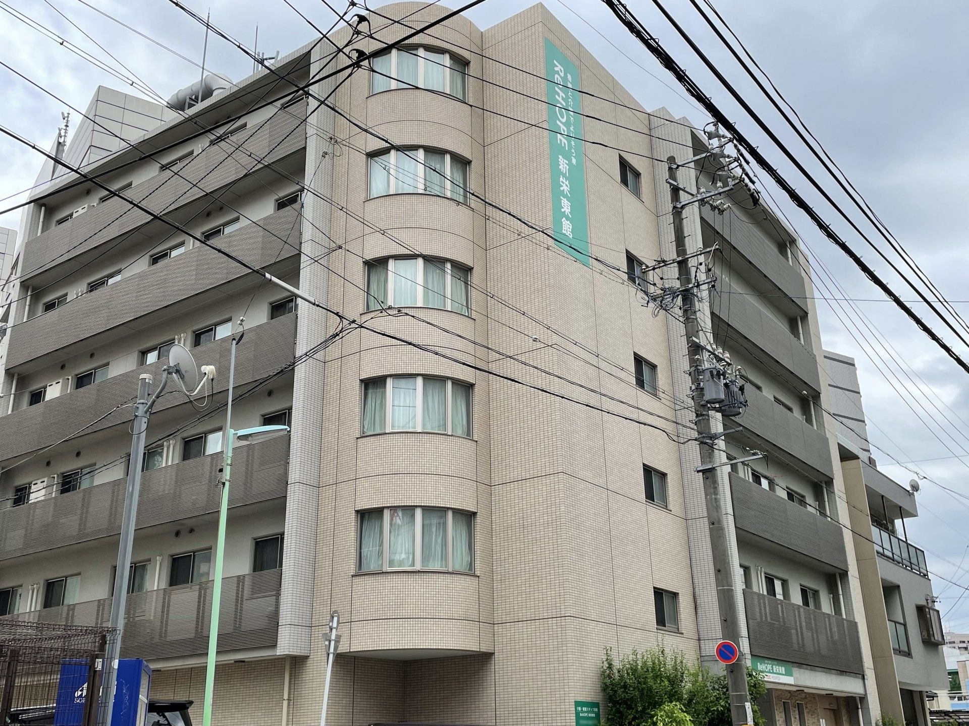 ホーム名が書かれているベージュの外観のどっしりと下建物の各フロアにベランダがある。