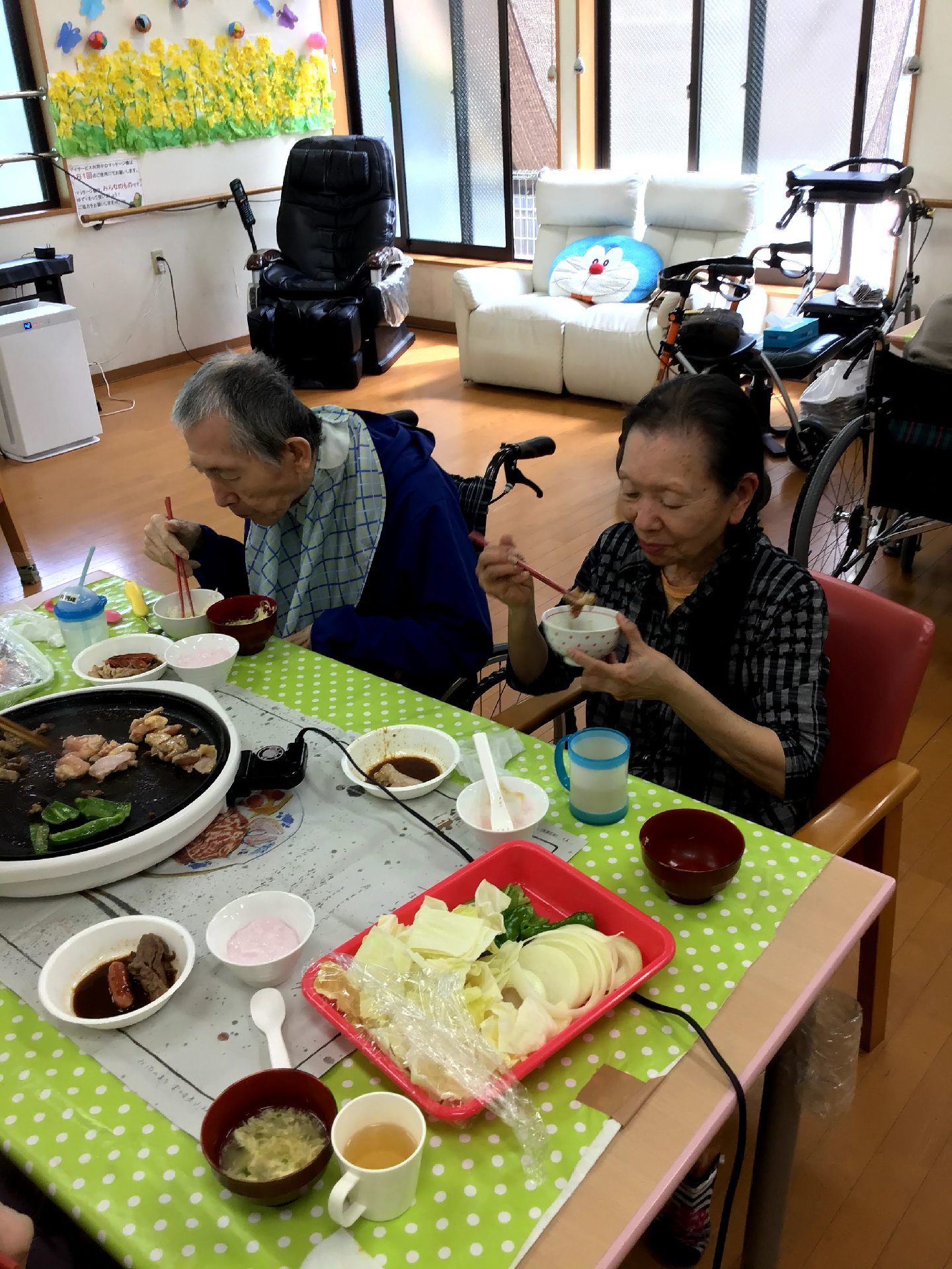ホットプレートを使って焼き肉を楽しむ入居者の様子。緑色のシートがテーブルに敷かれている。