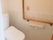 オレンジの呼び出しボタンが付いたトイレ。壁にはトイレットペーパーホルダーや手すりがある。