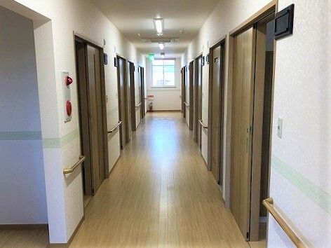 両サイドにドアが並んだまっすぐな廊下。壁には丸みのある手すりが設置されている。