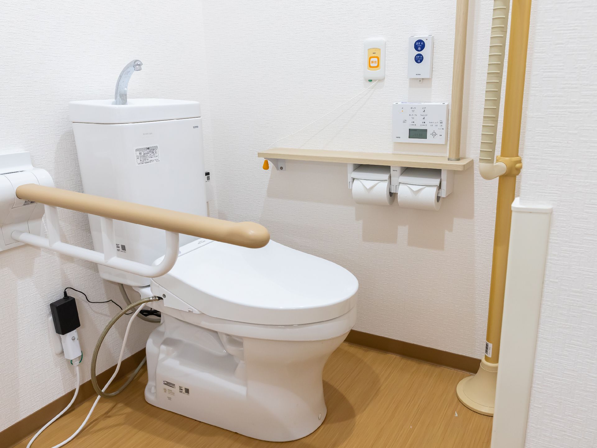 手すりと洗面台が設置されているトイレ