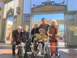 記念撮影をする車椅子に乗った高齢者と介助をするスタッフや仲間