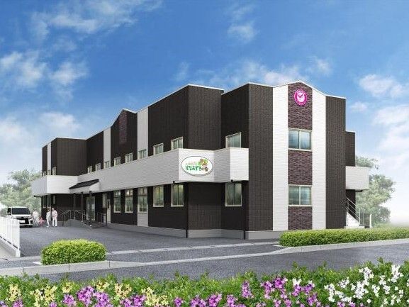 ダークグレーの２階建ての建物。敷地内に車が止まっている。外壁には住宅名も書かれている。