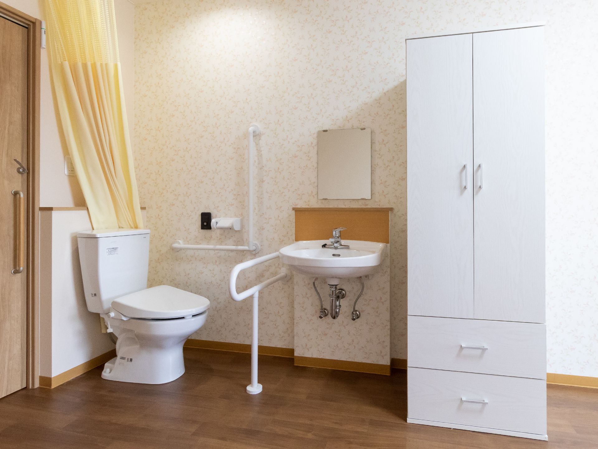 テーブルを囲んで笑顔で話しているピンクのポロシャツを着た女性スタッフと高齢女性。