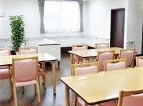 イスとテーブルがいくつも並んでいる施設内のリビング。リラックススペースのような場所