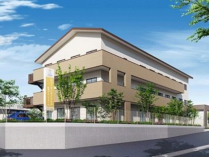 ３階建ての建物は白とベージュで周辺には緑が多くあり、看板にはホーム名が書かれている。