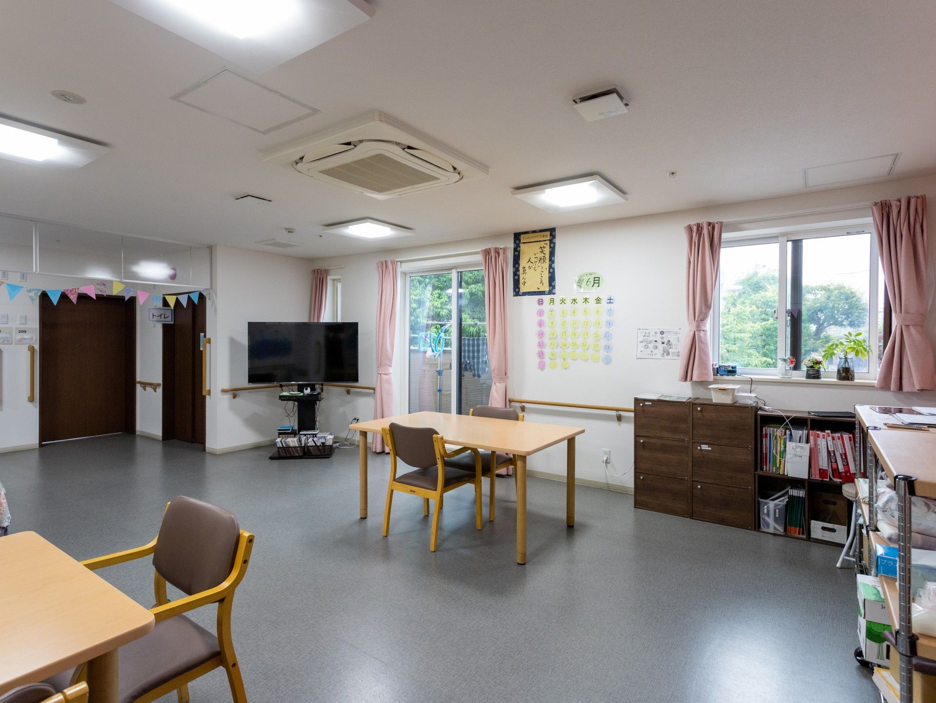 高齢夫婦と女性が芝生の上で話をしている様子。3人とも並んで座り、笑っている。