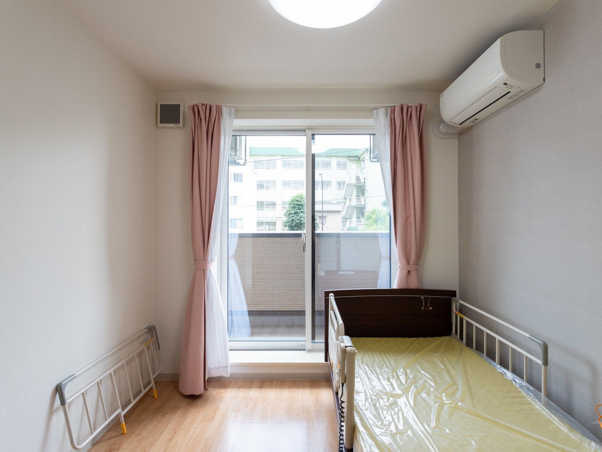 眼鏡をかけた車いすの男性入居者と女性スタッフが屋外での散歩を楽しんでいる。