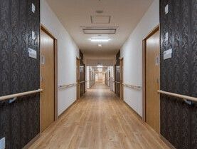 手すりが両側の壁に取り付けられている施設内の廊下の写真
