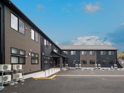 木造２階建てのケアガーデン鹿沼の外観写真。手前に駐車場がある様子