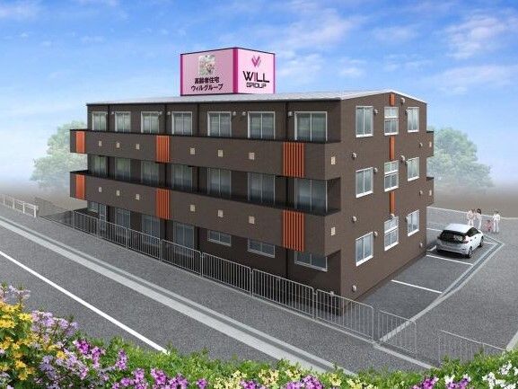 駐車場では子連れの家族が高齢者と話している。ブラウン系の３階建ての建物は窓が多くあり、各フロアにベランダがある。
