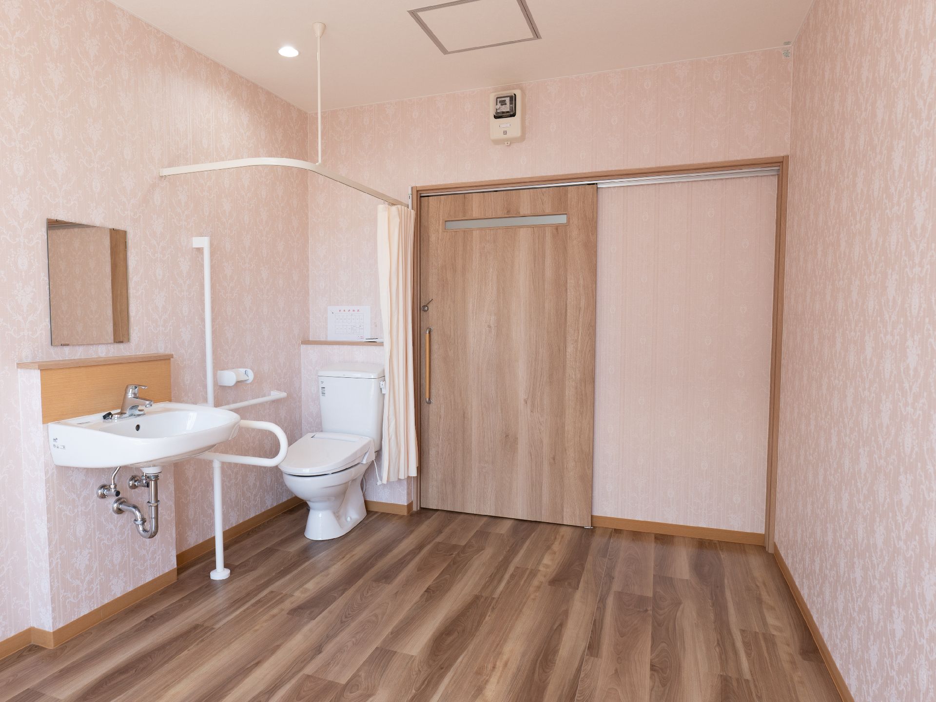 洗面台と洋式便器が置かれたピンクの壁の部屋