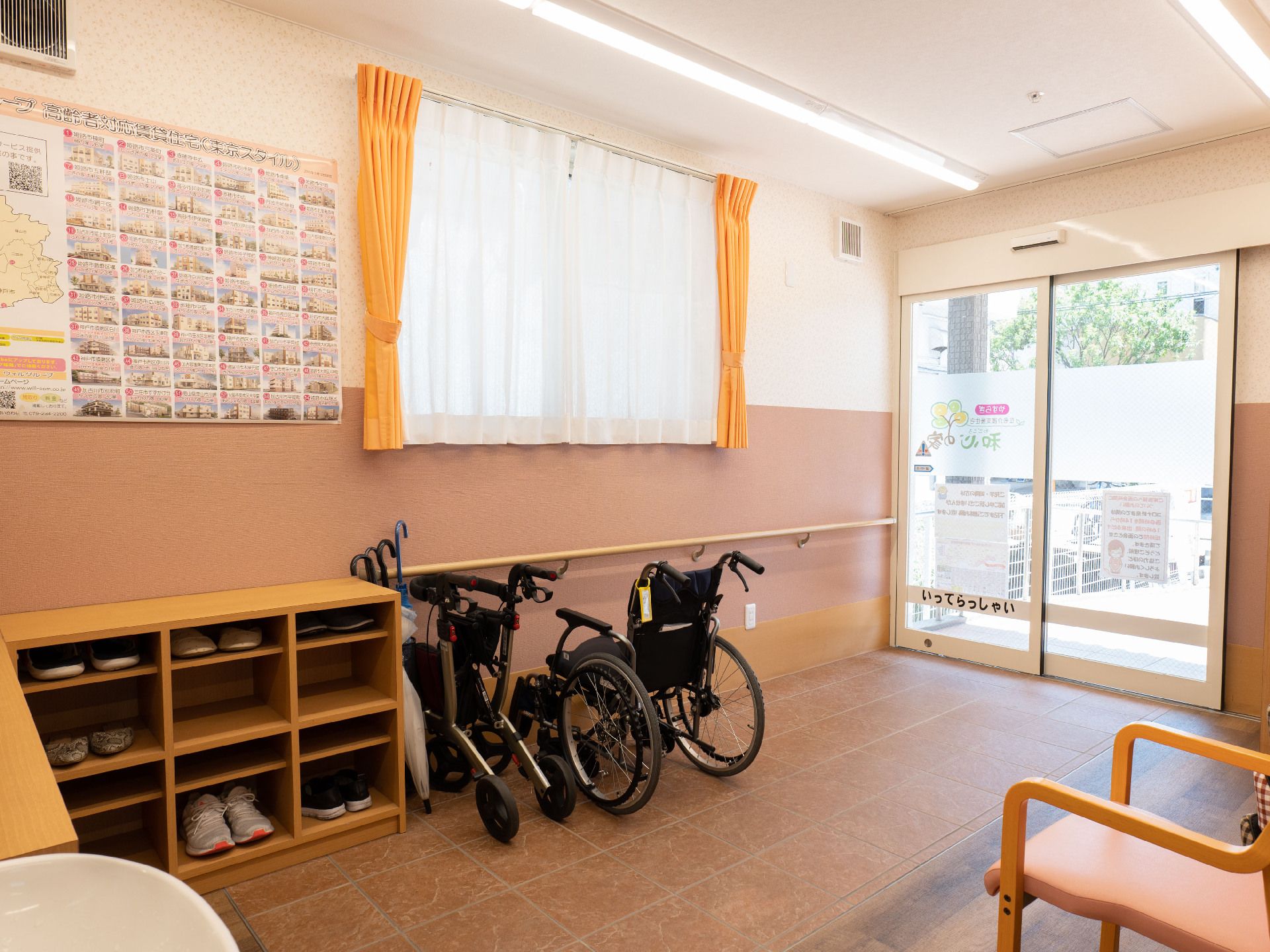 手すりのついた壁際に車いすと木製の靴箱が並んだ建物の入り口
