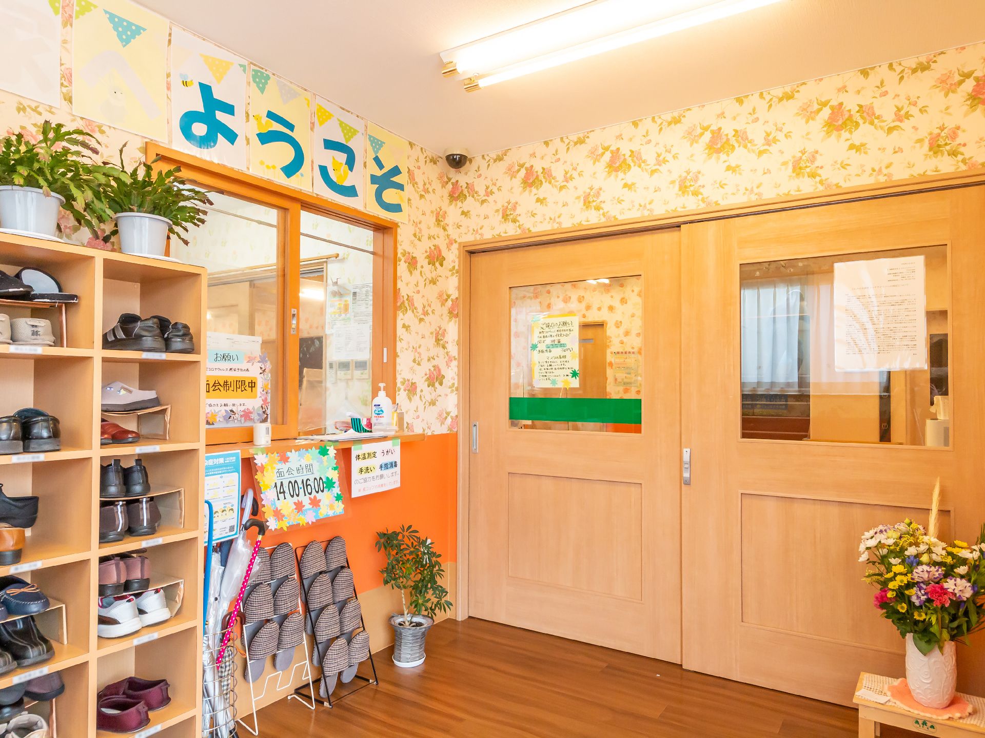 靴箱と受付口が配置された黄色い壁の部屋