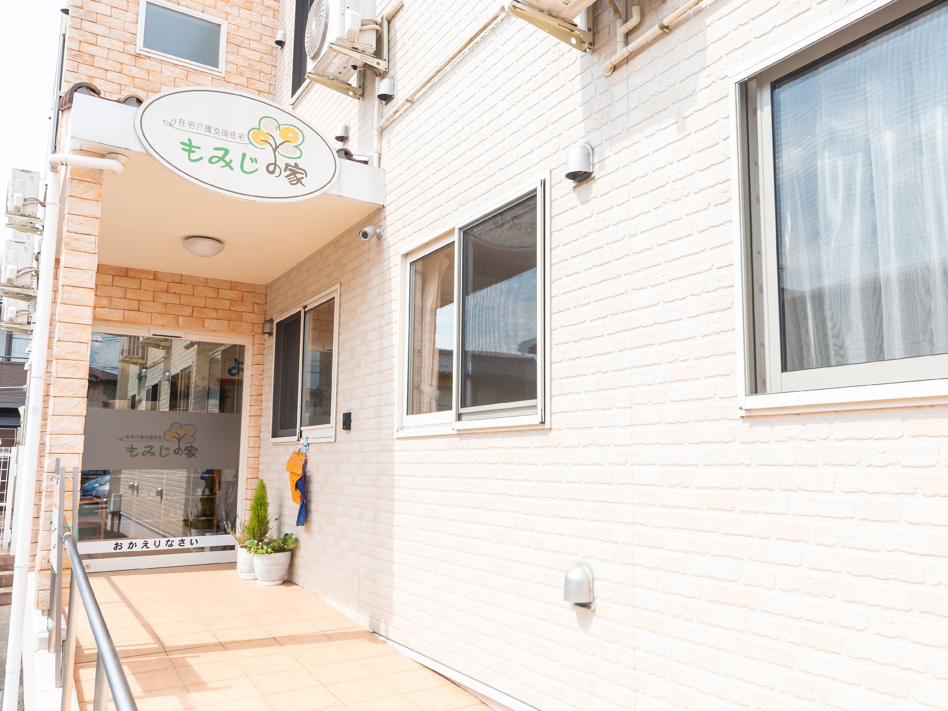 白い壁の建物の入り口に設けられた手すりが付いたスロープ