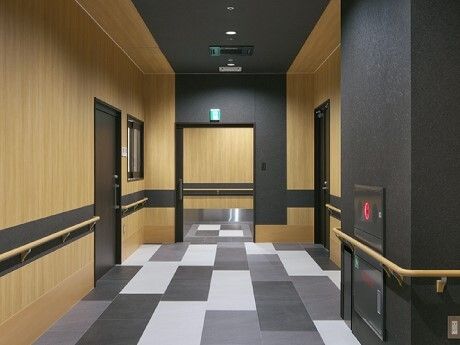 白と黒のモノトーンのフロアに木製の手すりが付いた壁。防災設備も設置されている館内。