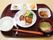和風ハンバーグに汁物、ゴマ豆腐や柿などが並べられたブラウンのトレー。
