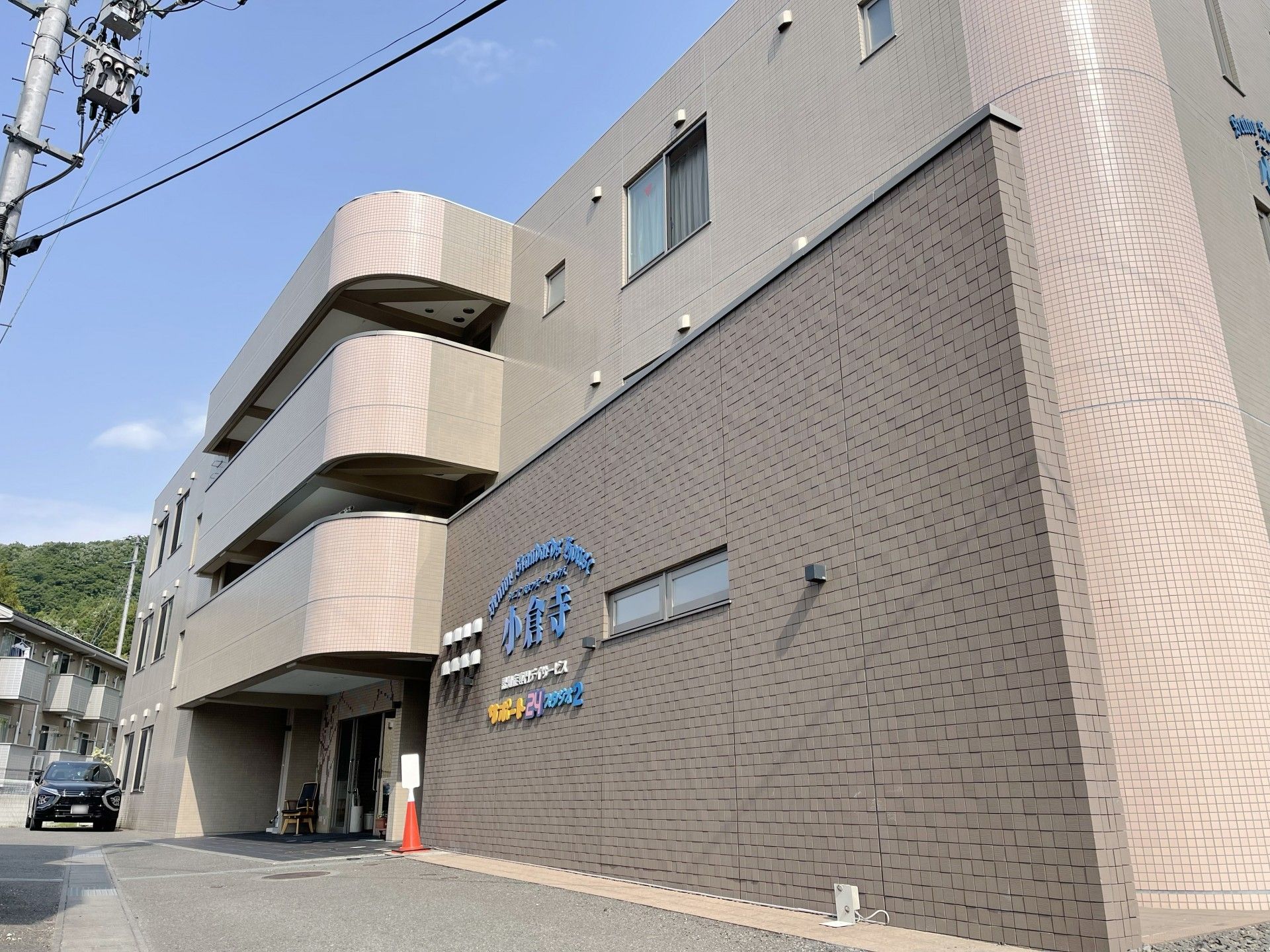 寝ている高齢者の女性に笑顔で話しかけている女性スタッフはエプロンを付けている。