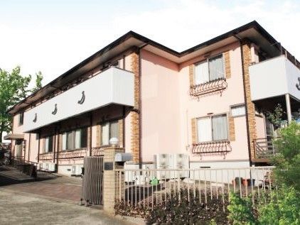 ベージュ系の建物は２階建て。家庭的な雰囲気で庭も付いている。