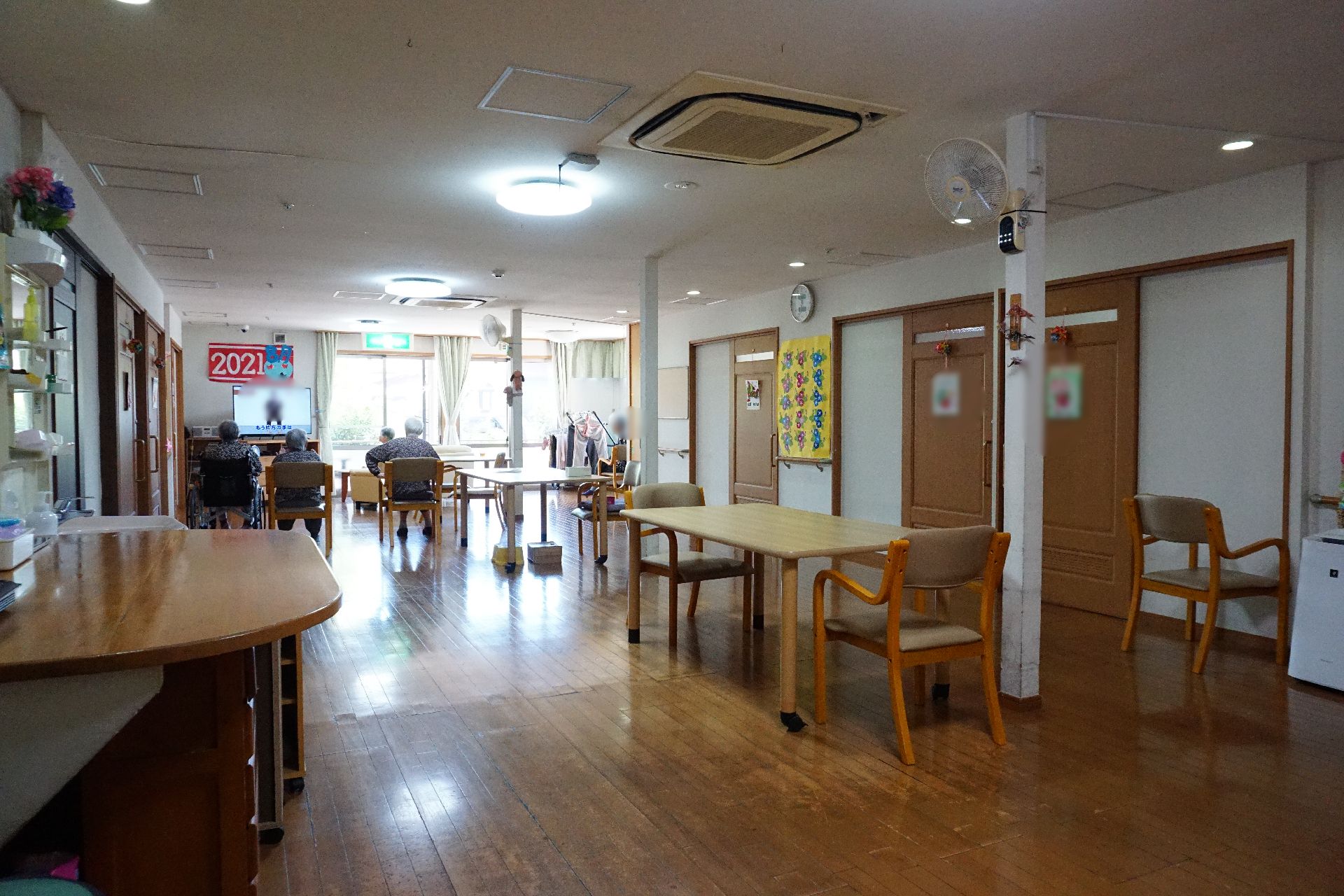天井にエアコンが取り付けられ、テーブル、椅子が置かれている共有スペース
