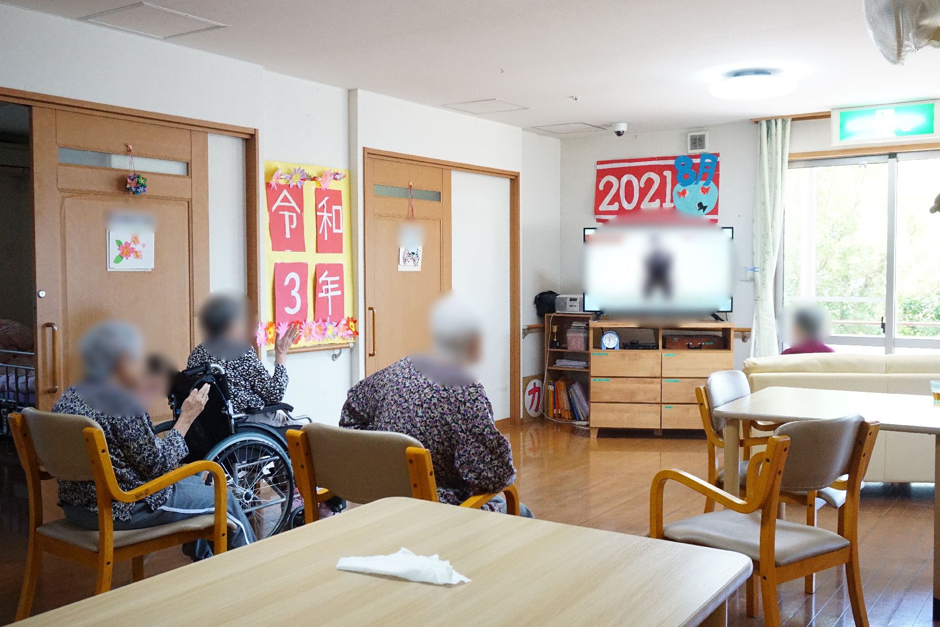 テレビが設置され、テーブルとイスが置かれている共有スペース